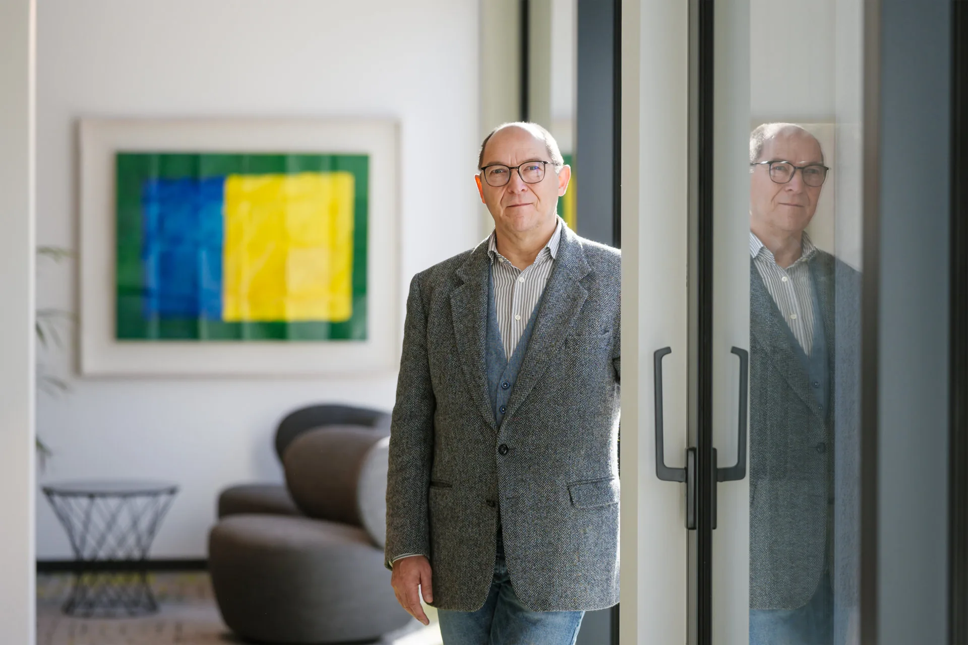 Joachim Wollschläger vor einer Glastür mit Spiegelung